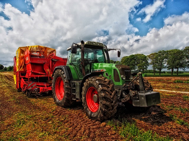 image of green and red tractor in field
